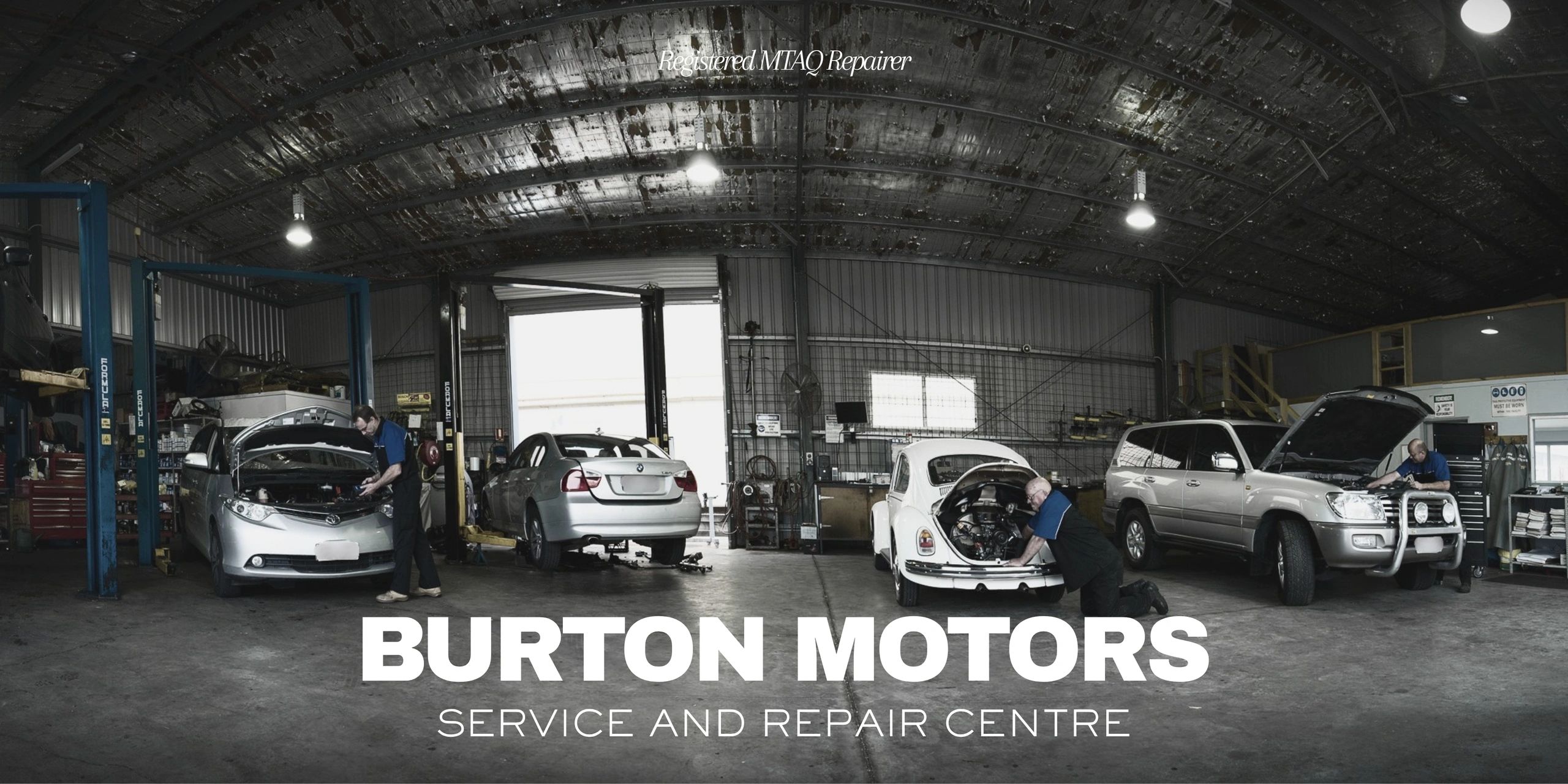 Car repair service garage with mechanics working on vehicles.