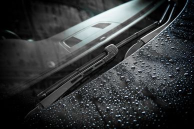 Car windshield with raindrops and wipers.