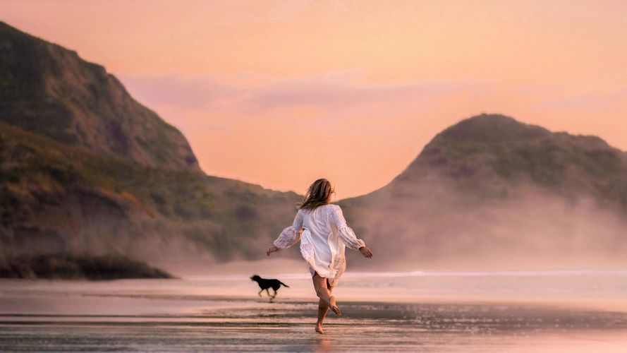 Woman running on the beach with a dog