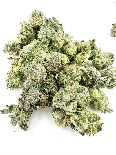 Close-up of dried cannabis buds on a white surface.