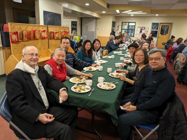 Group of people enjoying a meal together at a long table indoors.