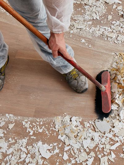 Person sweeping debris off the floor during renovation.