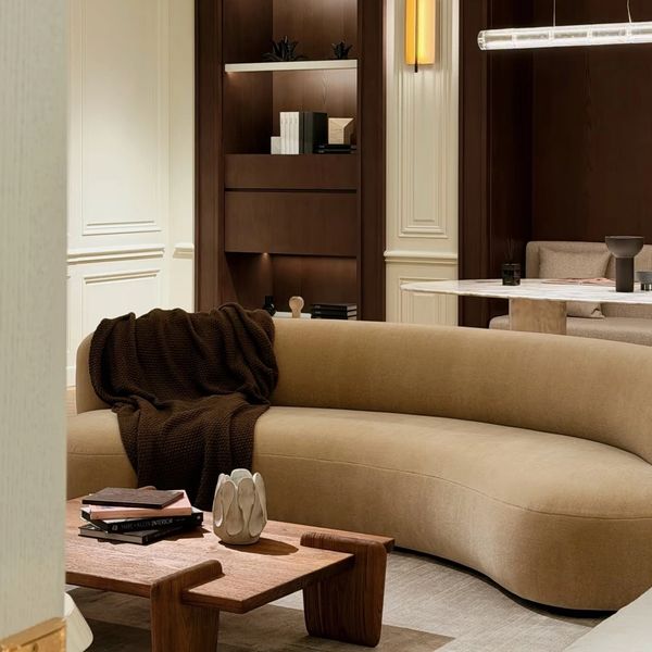 Modern living room with a curved beige sofa and wooden coffee table.