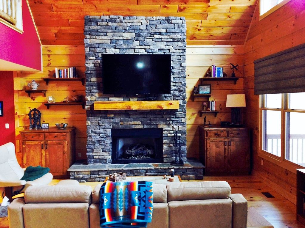 Cozy living room with stone fireplace and mounted TV.