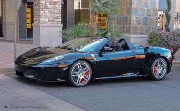 Sleek black Ferrari convertible parked on a city street.