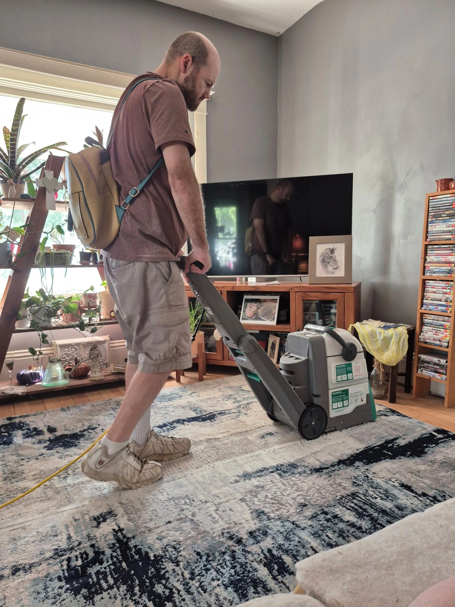 Man vacuuming a carpet in a living room.