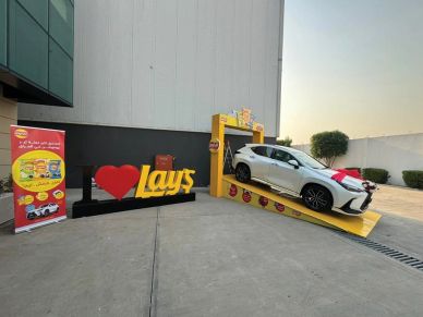 White car on a yellow ramp next to I love Lays sign.