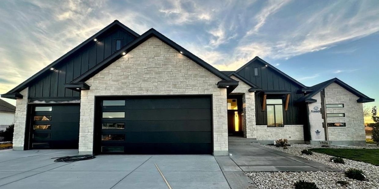 Modern house with black garage doors and stone facade.