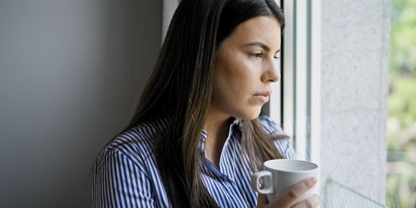 Woman gazing out the window, daydreaming, thinking about the intensive dreaming experience.