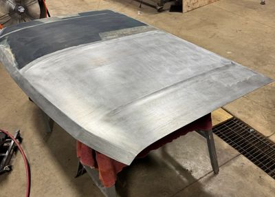 A car hood being sanded and prepped in a workshop.