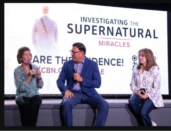 Three people discussing supernatural miracles on stage.