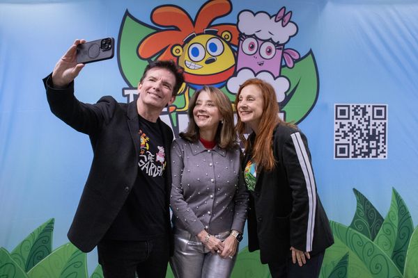 Three people taking a selfie in front of a colorful cartoon backdrop.