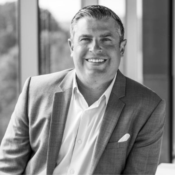 Smiling man in a suit jacket and white shirt.