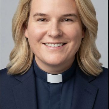 Person wearing a priest collar and suit jacket.
