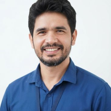 Smiling man in a blue shirt against a white background.