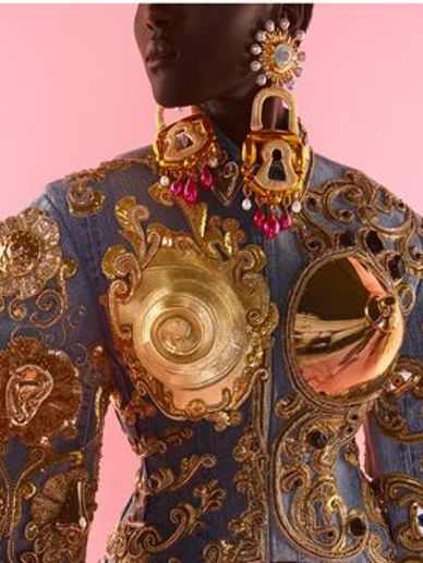 Close-up of an ornate jacket with gold embellishments and large lock earrings.