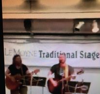 Two musicians playing guitars on a traditional stage.