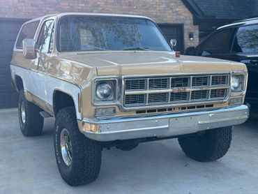 Vintage beige and white GMC SUV parked outside a house.