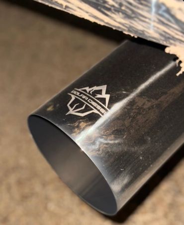 Close-up of a black SuperDiesel exhaust pipe on a vehicle.