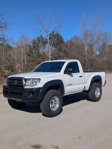 White Toyota Tacoma pickup truck parked outdoors on a sunny day.