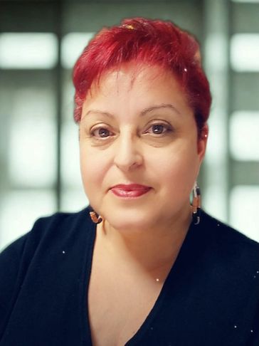 Portrait of a woman with vibrant red hair and a warm smile.
