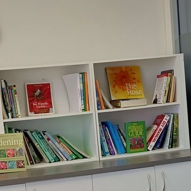 A modern meeting room with a white table, chairs, laptop, and bookshelves.
