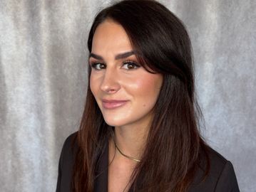 A confident woman with long dark hair and subtle makeup smiles gently.