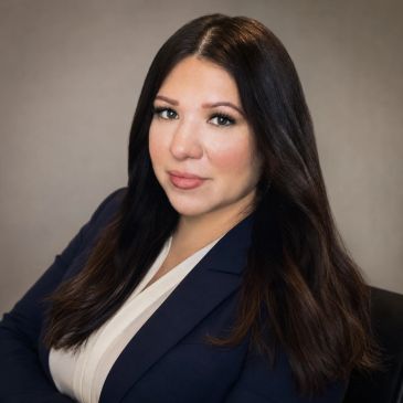 Professional woman in a navy blazer and white blouse.
