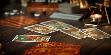Tarot cards spread out on a wooden table with a candle in the background.