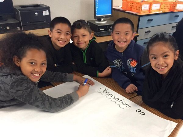 group of kids smiling and doing groupwork