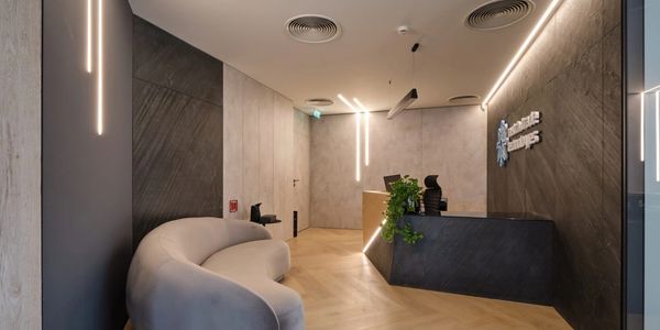 Modern office reception with curved sofa and sleek lighting.
