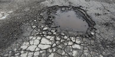 Parking lot with alligator cracking and pothole in need of asphalt crack repair and pothole repair