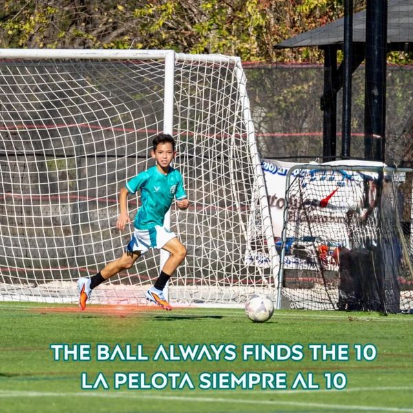 Young soccer player running towards the ball near the goal on a sunny day.