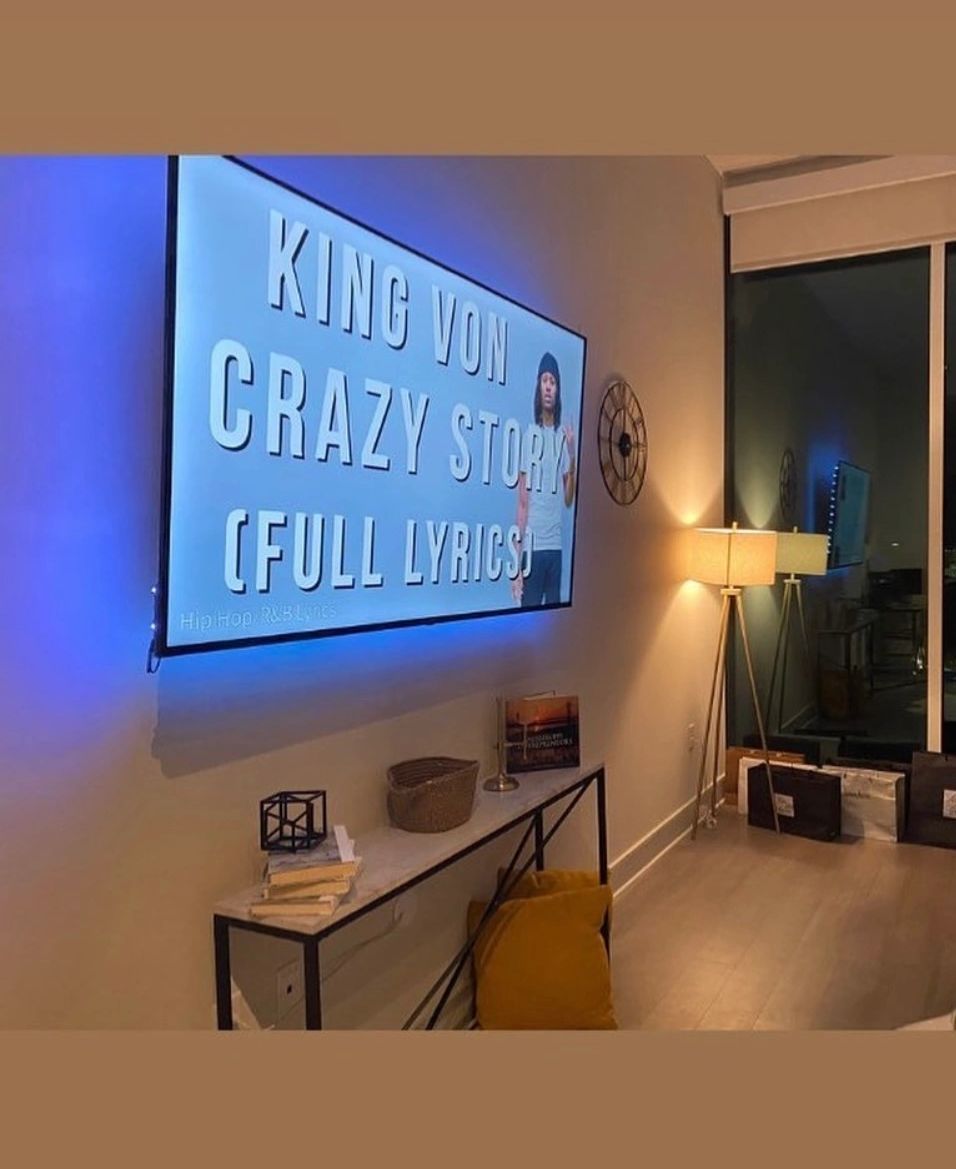 Modern living room with TV showing King Von Crazy Story lyrics and cozy lighting.