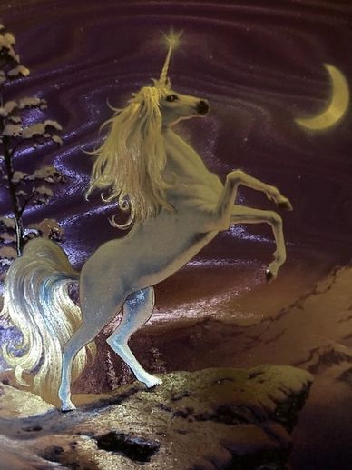 A majestic unicorn with a glowing horn stands on a rocky cliff under a crescent moon.