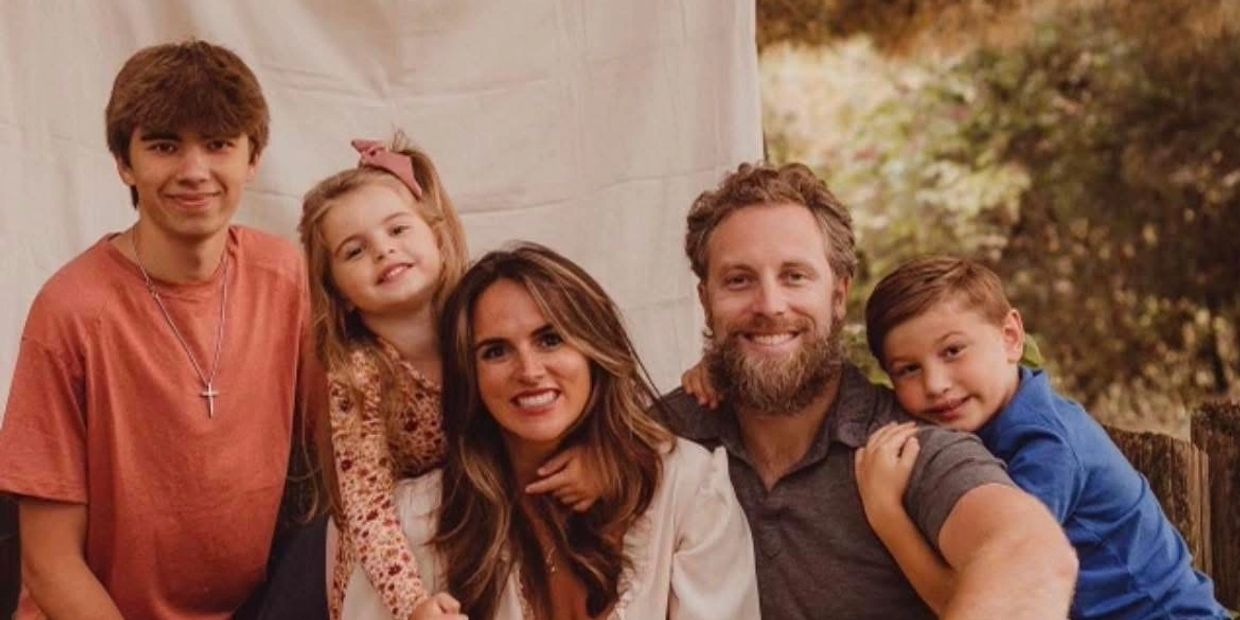 A happy family of five posing outdoors with smiles and warm autumn tones.