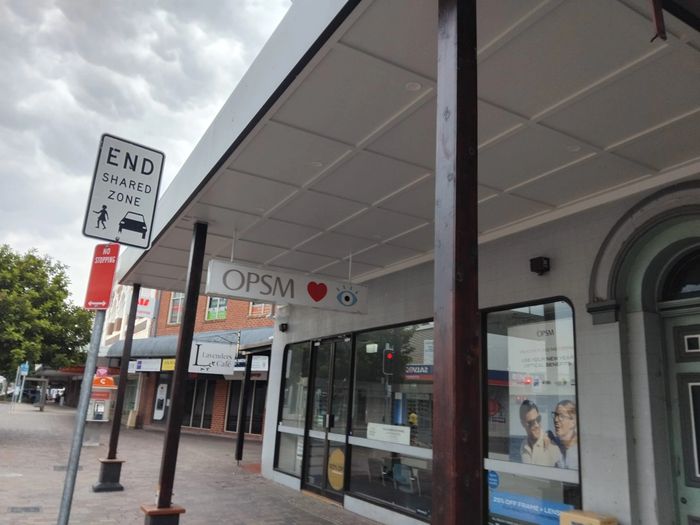 Street view with an 'End Shared Zone' sign and OPSM storefront.