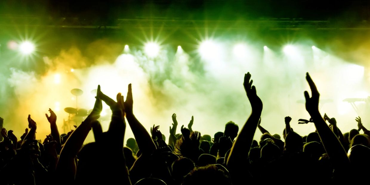 silhouettes of concert crowd in front of bright stage lights