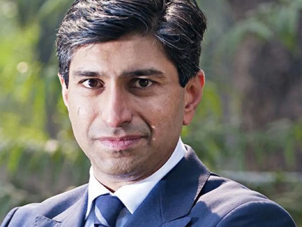 Confident man in a suit outdoors with greenery background.