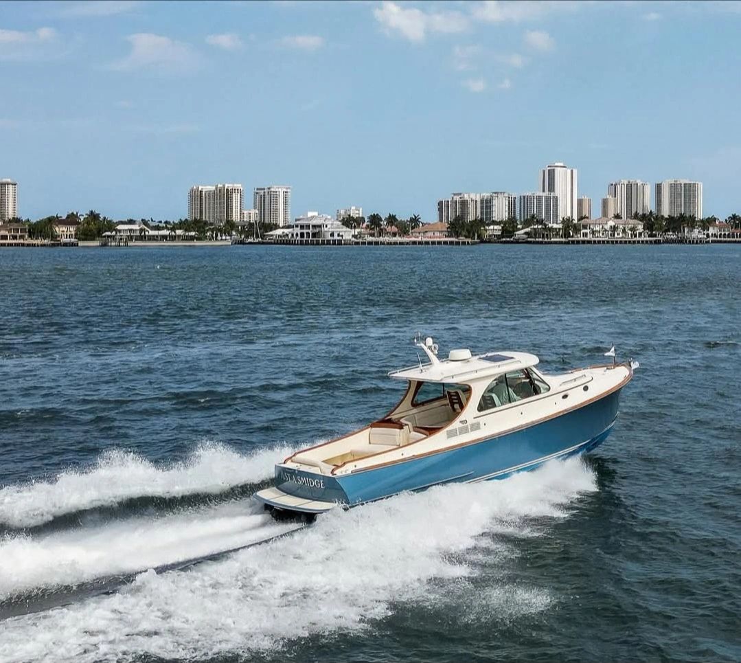 Blue and white motorboat speeding on water near city skyline.