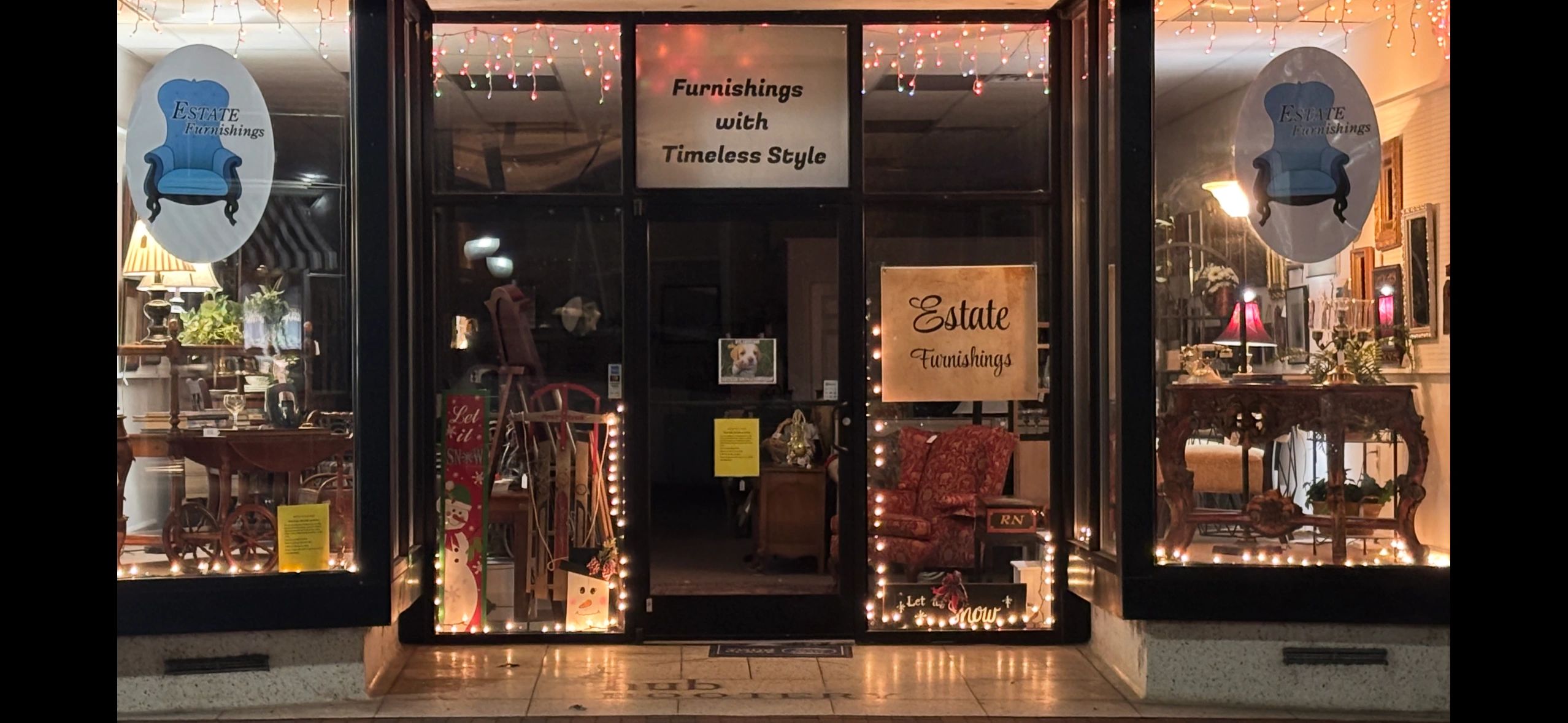 Cozy antique furniture store front decorated with warm lights and holiday themes.