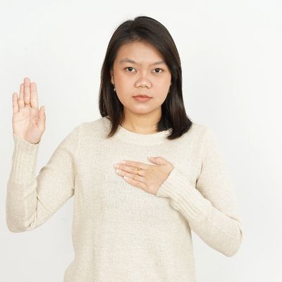 Woman making a pledge with one hand raised and the other on her chest.