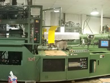 Large green industrial machine in a factory setting.