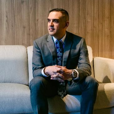 Man in suit sitting on a couch, looking to the side.