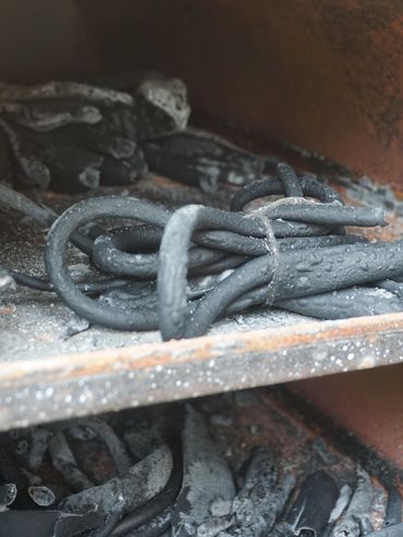 Close-up of blackened, burnt wires inside a rusty metal compartment.