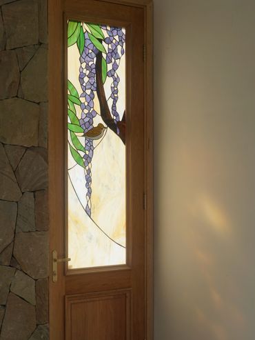 Wooden door with stained glass featuring purple flowers and a bird design.