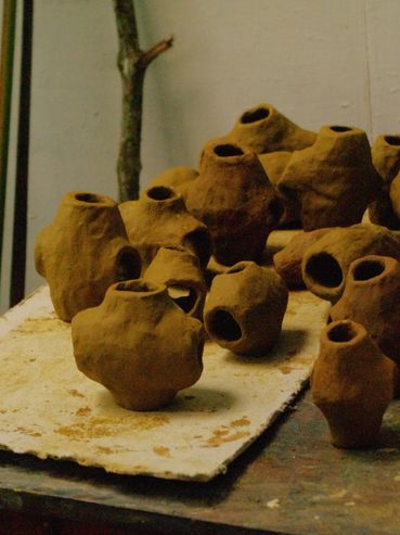 Handmade clay pots with rough textures arranged on a table.