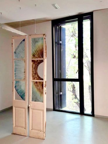 Art installation with doors featuring a large eye design in a minimal room.