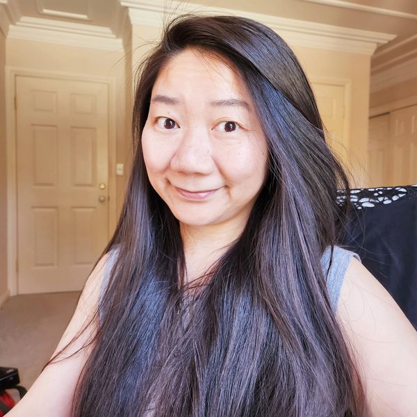Smiling woman with long dark hair in a warmly lit room.
