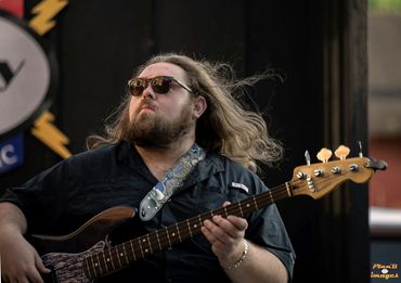 Bearded man playing bass guitar with sunglasses.